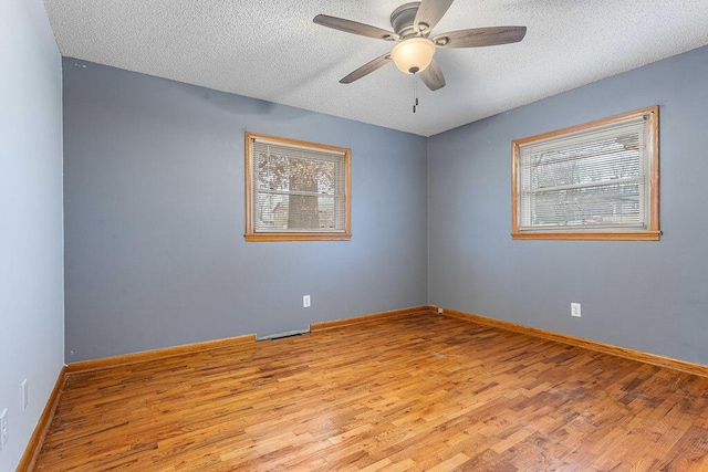 unfurnished room featuring plenty of natural light, ceiling fan, light hardwood / wood-style flooring, and a textured ceiling