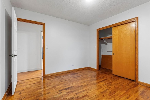 unfurnished bedroom featuring a closet, light hardwood / wood-style floors, and a textured ceiling