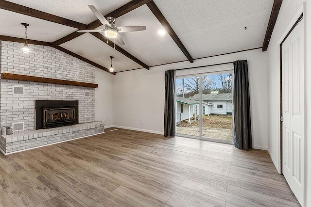 unfurnished living room featuring light wood-type flooring, a brick fireplace, a textured ceiling, ceiling fan, and lofted ceiling with beams