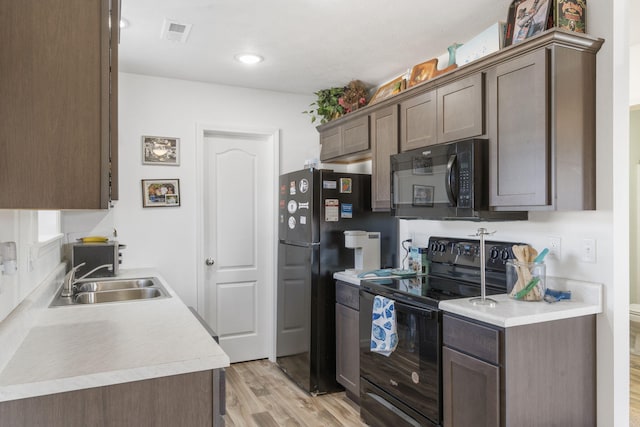 kitchen featuring black appliances, dark brown cabinets, light wood-type flooring, and sink