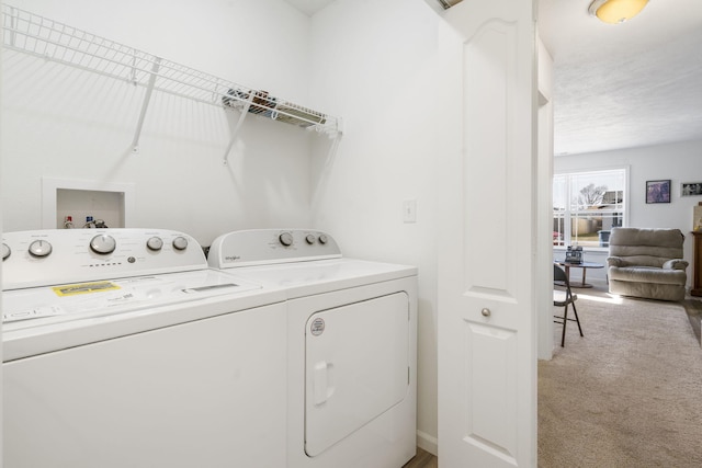 clothes washing area with washer and dryer, light colored carpet, and a textured ceiling