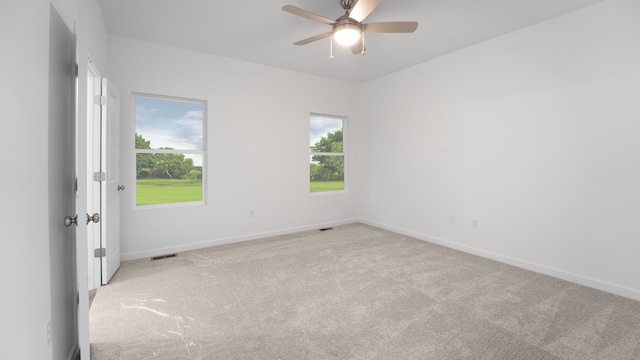 spare room featuring light carpet, a wealth of natural light, and ceiling fan