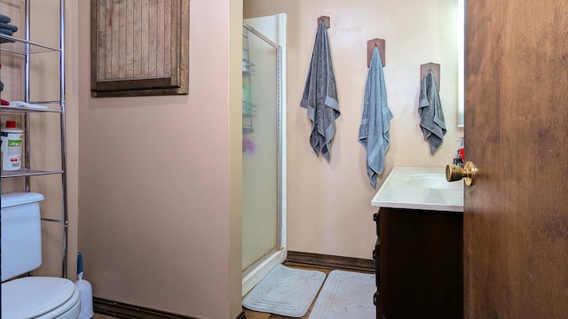 bathroom with a shower with door, vanity, and toilet