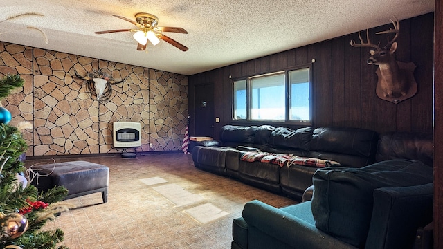 living room with ceiling fan, wood walls, a textured ceiling, and heating unit