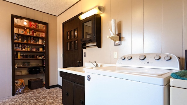 laundry room featuring cabinets, tile patterned floors, sink, a textured ceiling, and washing machine and clothes dryer