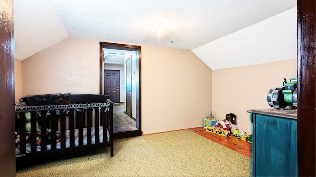 bedroom featuring carpet, vaulted ceiling, and a crib