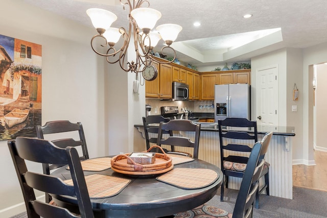 dining room featuring a chandelier, a textured ceiling, a tray ceiling, and hardwood / wood-style flooring