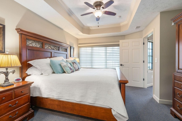 bedroom with ceiling fan, dark carpet, crown molding, and a tray ceiling