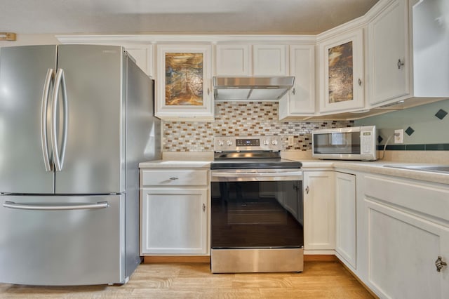 kitchen with white cabinets, appliances with stainless steel finishes, light wood-type flooring, and decorative backsplash