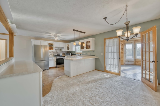 kitchen with pendant lighting, french doors, white cabinets, light hardwood / wood-style flooring, and stainless steel appliances