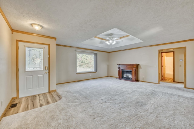 unfurnished living room featuring ceiling fan, ornamental molding, a textured ceiling, and light carpet