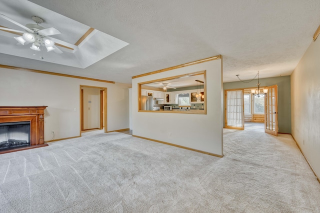 unfurnished living room featuring ceiling fan with notable chandelier, french doors, carpet, and a textured ceiling