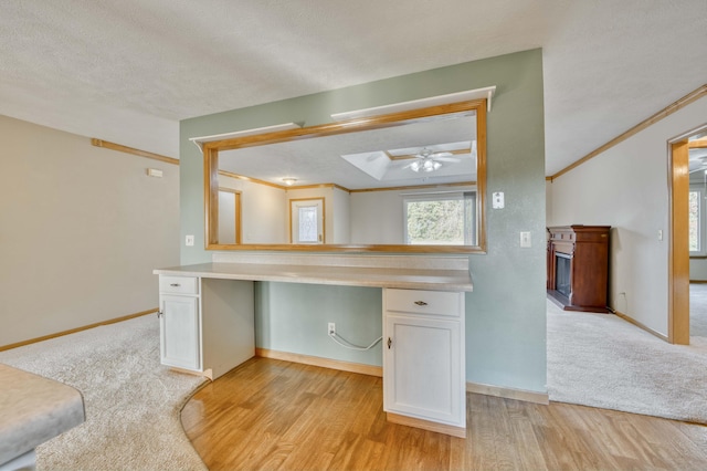 interior space featuring crown molding, built in desk, a textured ceiling, and light wood-type flooring