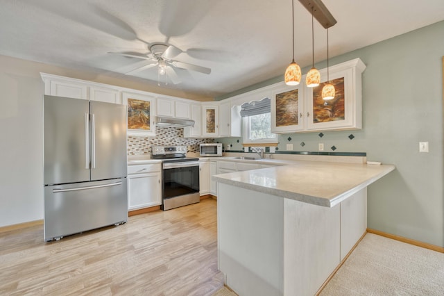 kitchen with white cabinets, hanging light fixtures, light wood-type flooring, appliances with stainless steel finishes, and kitchen peninsula