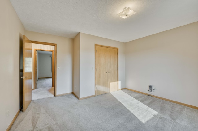 unfurnished bedroom featuring a closet, light colored carpet, and a textured ceiling