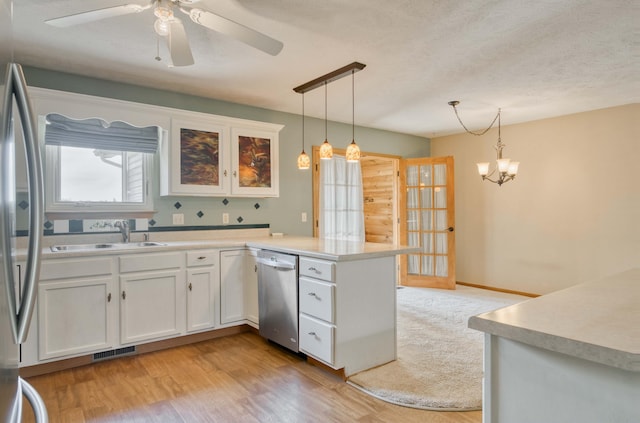 kitchen with stainless steel appliances, sink, light hardwood / wood-style flooring, white cabinets, and hanging light fixtures