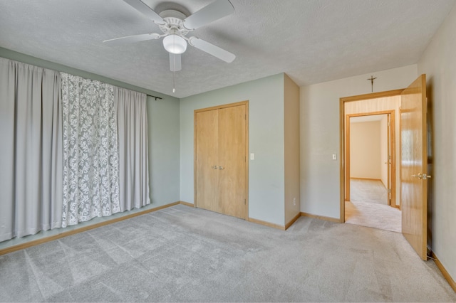 unfurnished bedroom with a textured ceiling, a closet, ceiling fan, and light colored carpet