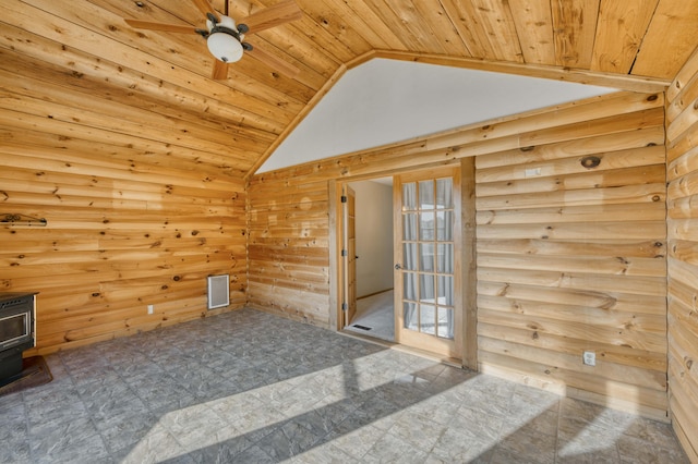 interior space with a wood stove, ceiling fan, wooden ceiling, lofted ceiling, and wooden walls