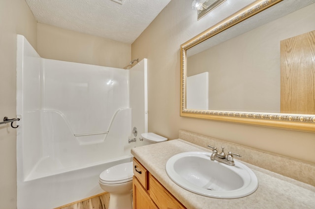 full bathroom with bathing tub / shower combination, hardwood / wood-style floors, a textured ceiling, toilet, and vanity