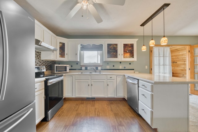 kitchen featuring white cabinets, appliances with stainless steel finishes, light hardwood / wood-style floors, and pendant lighting