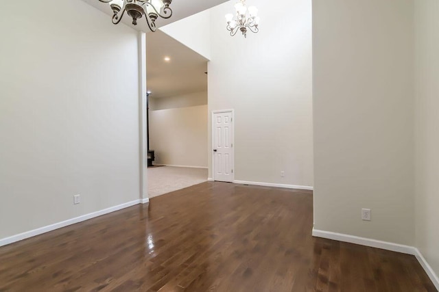 empty room with dark hardwood / wood-style floors and an inviting chandelier