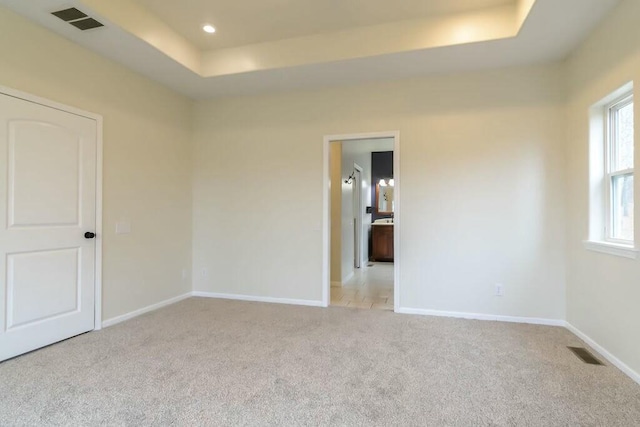 unfurnished room with a tray ceiling and light colored carpet