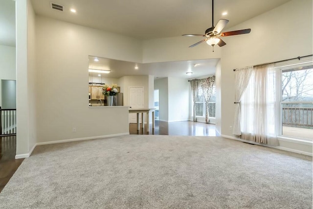 unfurnished living room featuring ceiling fan, high vaulted ceiling, and dark colored carpet