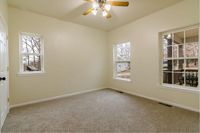 carpeted spare room featuring plenty of natural light and ceiling fan