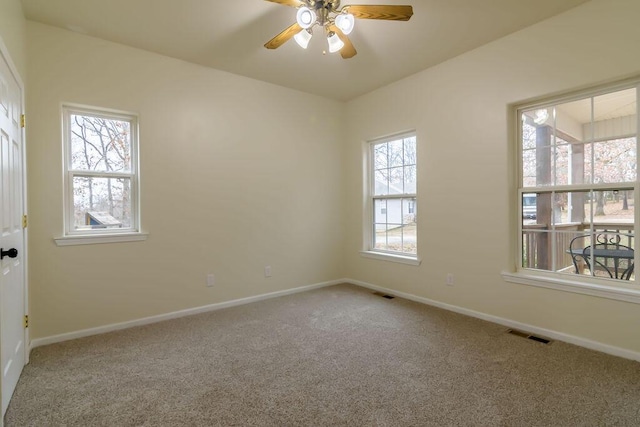 carpeted spare room featuring plenty of natural light and ceiling fan