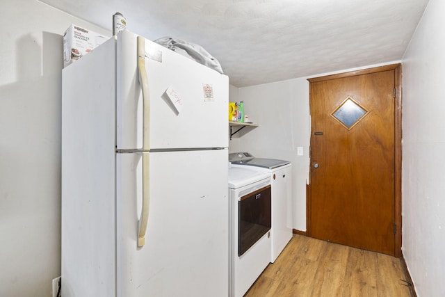 laundry room with washing machine and dryer, light hardwood / wood-style flooring, and a textured ceiling