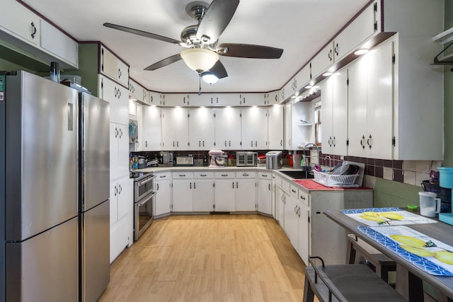 kitchen featuring white cabinets, sink, decorative backsplash, light hardwood / wood-style floors, and stainless steel appliances