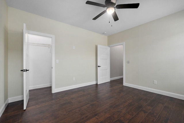 unfurnished bedroom with a closet, dark hardwood / wood-style floors, a spacious closet, and ceiling fan