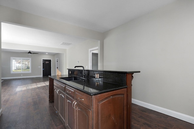 kitchen featuring ceiling fan, sink, dark hardwood / wood-style floors, and a center island with sink