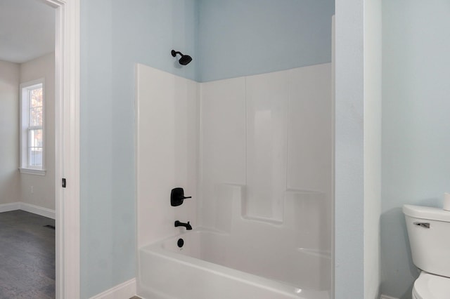 bathroom featuring hardwood / wood-style flooring, toilet, and tub / shower combination