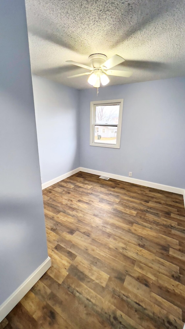 empty room featuring ceiling fan, dark hardwood / wood-style flooring, and a textured ceiling