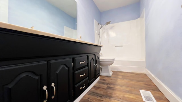 full bathroom featuring washtub / shower combination, hardwood / wood-style floors, vanity, and toilet