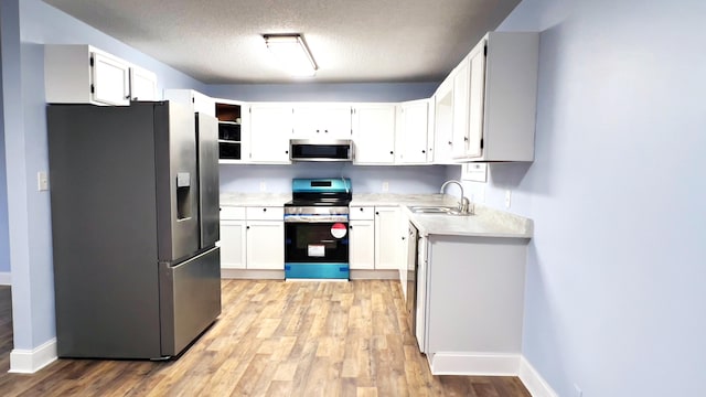 kitchen featuring white cabinets, sink, a textured ceiling, appliances with stainless steel finishes, and light hardwood / wood-style floors