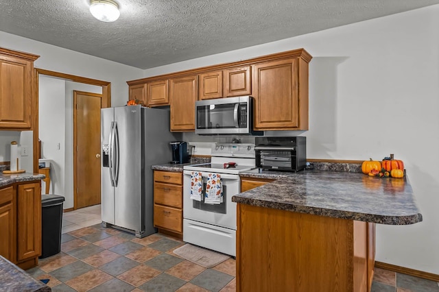 kitchen featuring a textured ceiling, a kitchen bar, kitchen peninsula, and stainless steel appliances