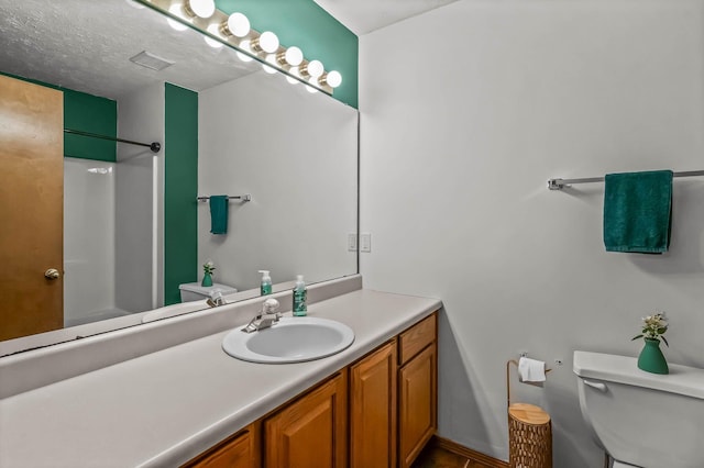 bathroom with walk in shower, vanity, a textured ceiling, and toilet