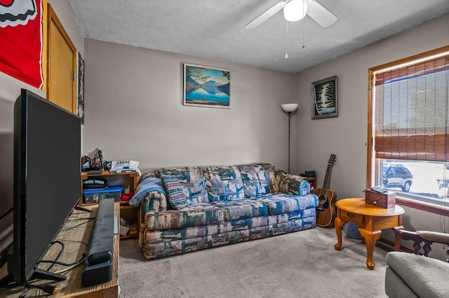 carpeted living room featuring ceiling fan and a textured ceiling