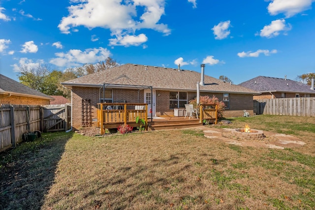 back of house with a deck, a lawn, and a fire pit