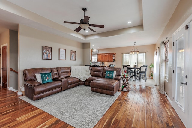 living room with baseboards, a tray ceiling, wood finished floors, and recessed lighting