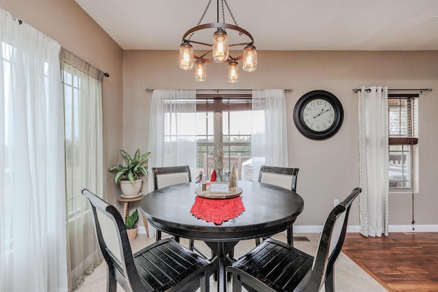 dining space featuring a healthy amount of sunlight, an inviting chandelier, baseboards, and wood finished floors