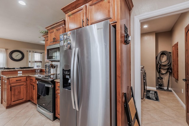 kitchen featuring a peninsula, brown cabinetry, light tile patterned floors, and stainless steel appliances