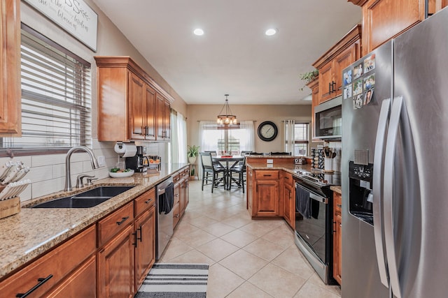 kitchen featuring appliances with stainless steel finishes, backsplash, a sink, and brown cabinets