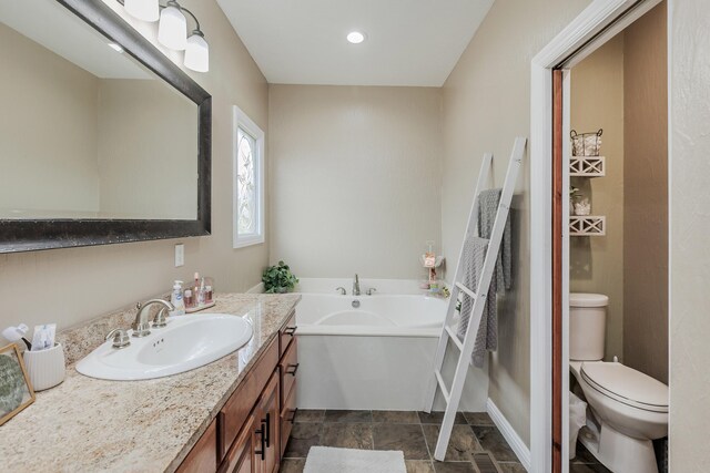 bathroom with a garden tub, vanity, and toilet