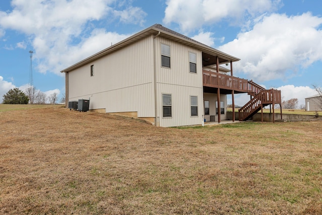 back of property featuring a lawn, stairway, a wooden deck, and central air condition unit