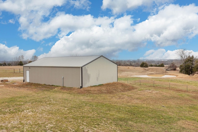 view of pole building with a yard, a rural view, and fence