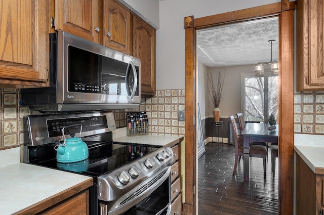 kitchen featuring tasteful backsplash, a textured ceiling, stainless steel appliances, and dark hardwood / wood-style floors