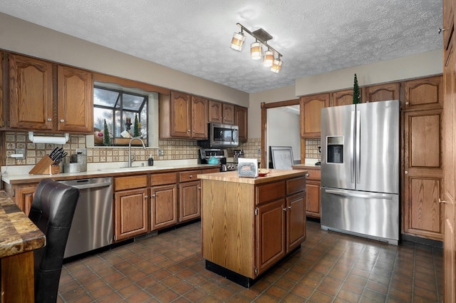 kitchen with appliances with stainless steel finishes, a center island, a textured ceiling, and sink